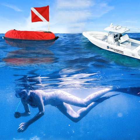 Inflatable Dive Float Buoy With Flag, 29 Inch Surface Marker For Scuba, Freediving, Snorkeling, And Spearfishing, High Viz Red And White Signal, Rugged Cordura Nylon Cover, Go To Training Safety Float near a diver and boat on the water.