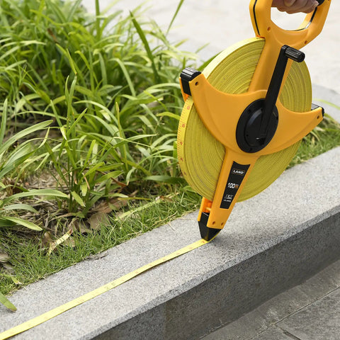 Heavy Duty Fiberglass Tape Measure 330 Feet 100 Meters Open Reel being used on rough site near grass and pavement