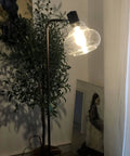 Farmhouse Bubble Glass Floor Lamp With Adjustable Tall Pole in living room, lit, showing hand blown glass shade and oil rubbed bronze finish.