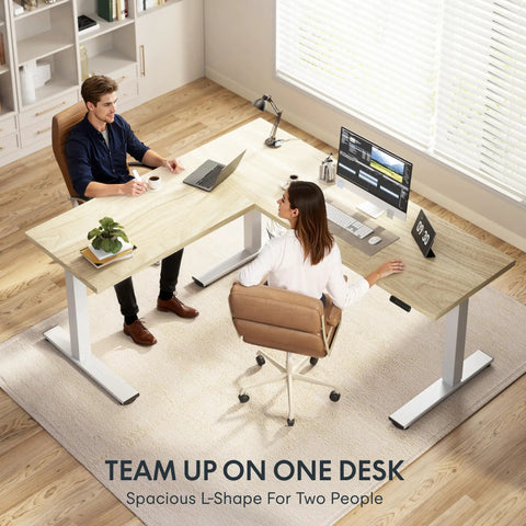 Massive 63x47 Inch L-Shaped Electric Standing Desk In Warm Maple Finish with two users working.