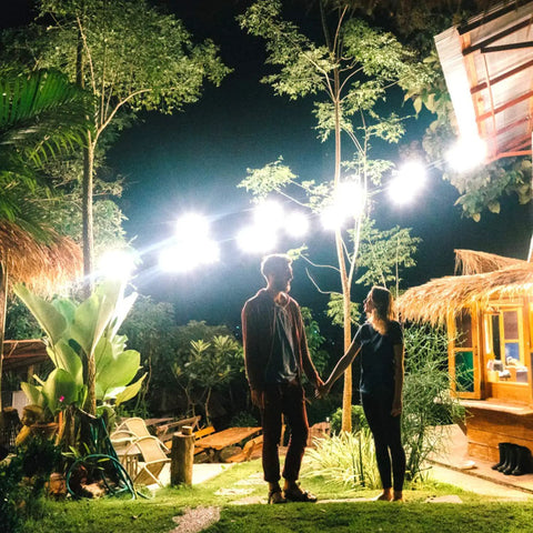 JUDYSSY Outdoor Led Floodlights with Remote Control illuminating a garden setting at night with two people holding hands.