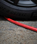 Reliable Workhorse Lightweight Hybrid Air Compressor Hose 3/8 Inch By 10 Feet under a car tire with caution label visible.
