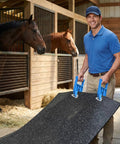 Man using Heavy Duty Horse Stall Mat Grippers Set Of 2, Serrated Grip For Tight Fit And Easy Move, Slippage Free Handling, Mat Lifter Tool To Shift Large Carpets Safely, Durable Stall Flooring Accessory For Quick Adjustments on a rubber mat in a horse stall