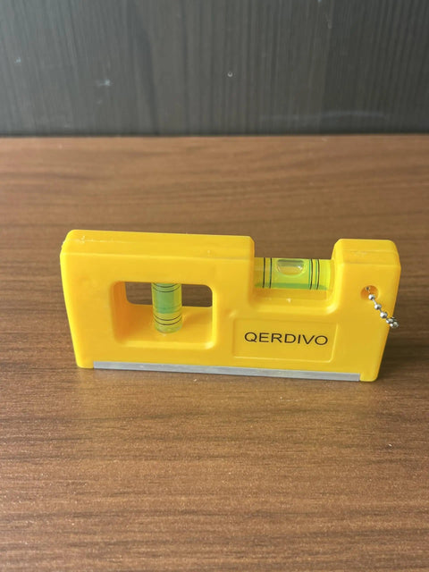 QERDIVO Spirit Levels Mini Horizontal Vertical Pockets Spirit Levels Spirit Bubble Leveler on wooden surface, showing yellow compact design.