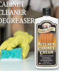 Kitchen Cabinet Creme Cleaner And Grease Remover For Wood Surfaces, No Fuss 16 Oz, yellow-gloved hand with sponge and product