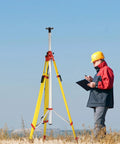 Surveyor with a Giant 157 Inch Elevating Tripod For Rotary Lasers And Surveying Gear, standing in an open field with equipment.