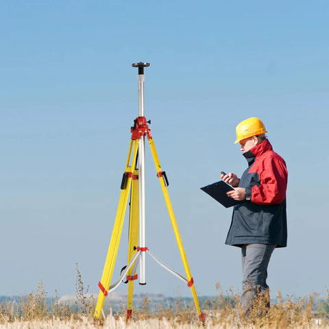 Surveyor with a Giant 157 Inch Elevating Tripod For Rotary Lasers And Surveying Gear, standing in an open field with equipment.