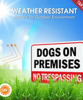 Built Solid 10x7 Inch Dogs On Premises No Trespassing Signs 2 Pack Rust Free Reflective Aluminum in grass under sunny sky.