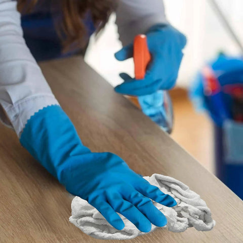 Person wearing blue gloves cleaning a surface with Premium White Terry Cloth Rags 25 Lb Bag Two Pack Beast Absorbent Cleaning Rags For Garage, Industrial Use, Housekeeping, And Multipurpose Spill Cleanup.