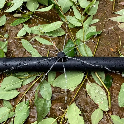 200 Pack Adjustable Drippers For Micro Irrigation attached to black tubing watering plants with 8-jet spray pattern.
