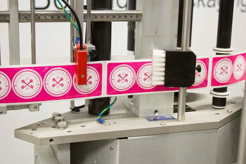 Heavy Duty Compact Modular Label Applicator shows labels aligned on a steel frame, designed for efficient factory use.