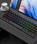 RGB mechanical keyboard on a desk with a tablet and cup, showcasing sleek office setup.