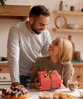 Couple in a kitchen exchanging a gift with pastries and coffee on the table
