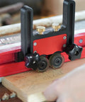 Close-up of Two Piece Adjustable Table Saw Stock Guides Featuring Slick Aluminum Brackets And Dead On Urethane Rollers in use on wood.