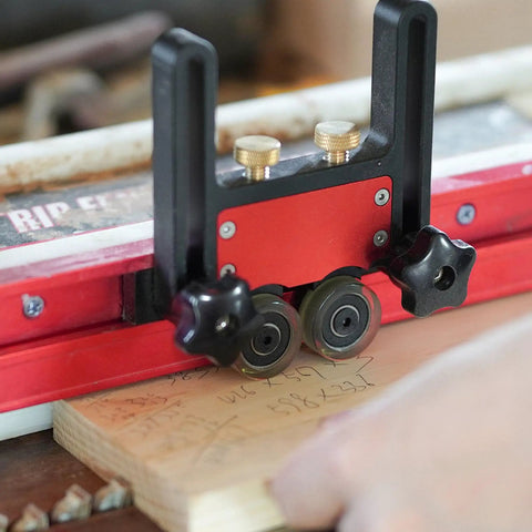 Close-up of Two Piece Adjustable Table Saw Stock Guides Featuring Slick Aluminum Brackets And Dead On Urethane Rollers in use on wood.