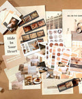 Complete Scrapbook Kit With 114 Pieces Aesthetic Supplies for Junk Journaling including posters, stickers, and paper on a table.