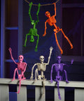 Spooky Hanging 16 Inch Posable Skeleton Set for Halloween Decor in various colors on porch rail and hanging from rope.