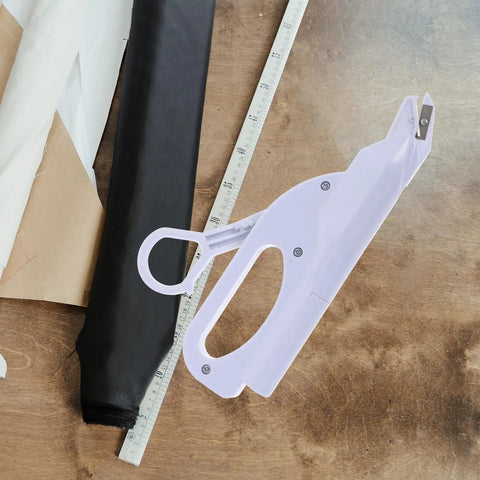 Cordless Electric Scissors For Fabric Cutting Handheld Sewing Tool With Safety Lock And Protective Cover Rechargeable Battery Operated Machine on a wooden surface with fabric and ruler.