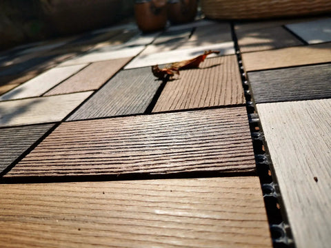 Close-up of Durable Wood Plastic Composite Patio Deck Tiles With Interlocking Design For 3D Random Pattern DIY Floor Tiles, outdoor setup.
