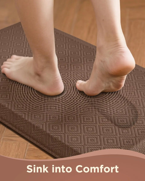 Feet stepping on Anti Fatigue Kitchen Floor Mat 20 By 32 Inches Three Quarter Inch Thick Cushioned Ergonomic Standing Pad Waterproof Surface Non Slip Bottom For Home Office Sink Brown on wooden floor.