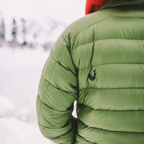 Person wearing a green puffer jacket outdoors, showcasing the jacket's material suitable for Tenacious Tape Repair Patches