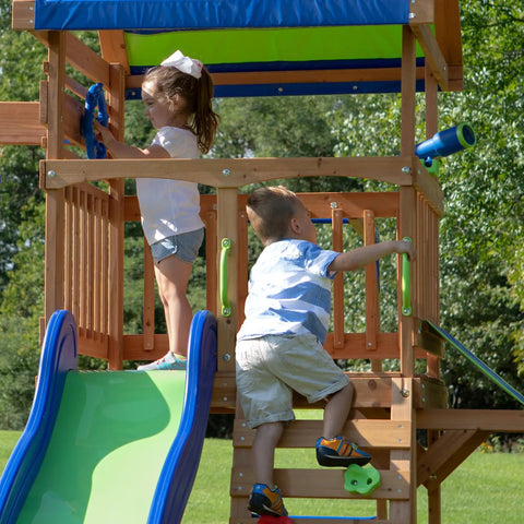 Children playing on Beachfront Cedar Wood Swing Set With Wave Slide Elevated Deck Canopy Monkey Bars Rock Wall Ladder Shaded Picnic Area Snack Bar Window Belt Swings Trapeze Sandbox Playset For Kids