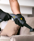 A person using professional black nitrile gloves while operating a vacuum cleaner for cleaning purposes.