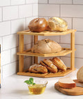Total Kitchen Game Changer, Super Handy Bamboo Corner Shelf, 3 Tier Plate Rack holding bagels and bread, natural bamboo material.