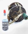 BP2000 Dry Powder Lubricant For Triggers Bores Bolts And Slides Reduces Friction 0.1 oz bottle next to an antique reel