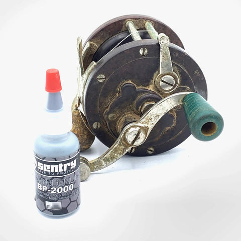 BP2000 Dry Powder Lubricant For Triggers Bores Bolts And Slides Reduces Friction 0.1 oz bottle next to an antique reel