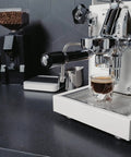 Next Level Home Bar Essentials Italian Handcrafted Espresso Machine With Heat Exchanger And E61 Manual Controls Badass Stainless Steel Chassis Three Liter Tank Fresh White Finish Straight Fire Quality For Every Coffee Geek brewing espresso shot on kitchen countertop.