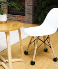 White chair with black 40 Pack Precut Tennis Balls For Furniture Legs And Floor Protection under legs near a wooden table.