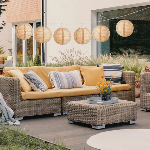 Outdoor patio with 12 Pack 8 Inch Burlap Paper Lanterns Round Chinese Lanterns for Farmhouse Boho Home Decor hanging above wicker sofa.