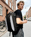 Man walking with TSA Friendly Carry On Travel Backpack for Men and Women With 180 Degree Full Opening Waterproof Pocket.