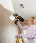 Person using FLEXiO 570 Handheld HVLP Paint Sprayer For Home Projects, Sprays Unthinned Latex on ceiling from a ladder.