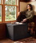 Heavy Duty 160 Gallon Deck Box Crafted From Weatherproof Resin With Secure Locking Lid used as a coffee table by a window.