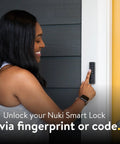 Woman using Slick Smart Deadbolt Lock With Keyless Entry with finger on keypad beside door.