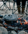 Heavy Duty Dutch Oven Lid Lifter with Coil Handle lifting a pot over campfire, outdoor scene, ideal for BBQ and outdoor cooking