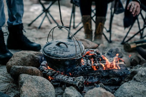 Heavy Duty Dutch Oven Lid Lifter with Coil Handle lifting a pot over campfire, outdoor scene, ideal for BBQ and outdoor cooking