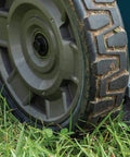 Close-up of the wheel of a Pro Grade 21 Inch Cordless Self Propelled Lawn Mower on grass, showcasing its durable design.