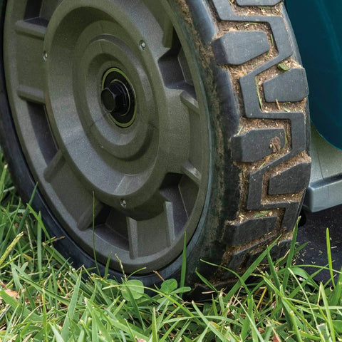 Close-up of the wheel of a Pro Grade 21 Inch Cordless Self Propelled Lawn Mower on grass, showcasing its durable design.