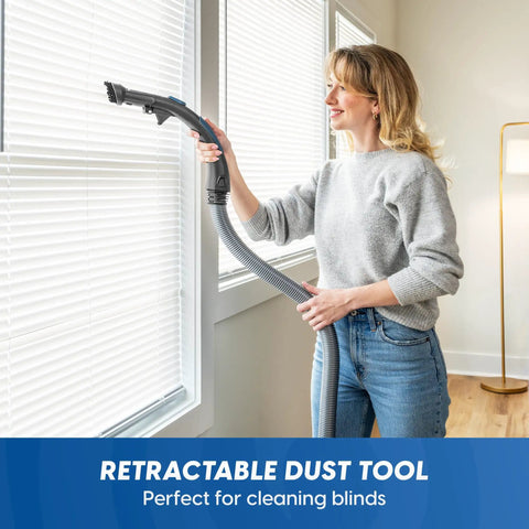 User using the retractable dust tool of a Quiet Bagless Canister Vacuum With Kickass Suction For Whole Home Cleaning.
