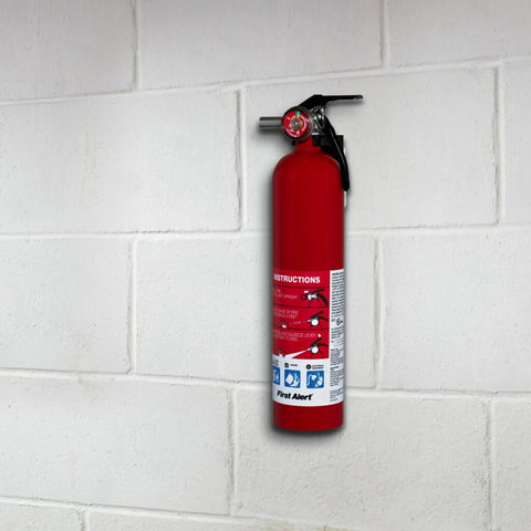 Red fire extinguisher mounted on a white brick wall indoors, showing safety label and nozzle.