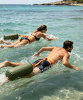 Two people swimming with the Do It All 3 In 1 Inflatable Water Weight Bag For Camping, Swim Float And Tent Anchor, 10L Green
