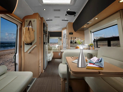 Interior view of a motorhome with a Lanterna Lux Satin Nickel LED Touch Lamp Two Pack on the dining table, beach view outside.