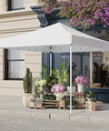Easy Up 10x10 Pop Up Canopy Tent With Heavy Duty Frame set up next to a building, providing shade for plants and decorations.