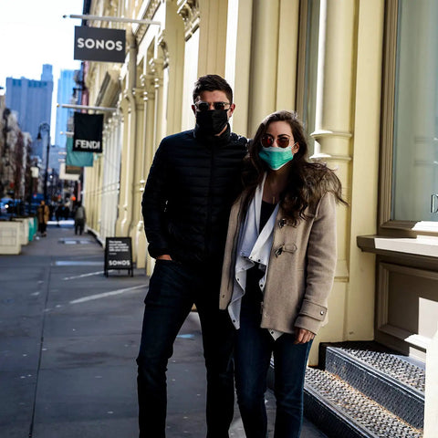 Two people wearing face masks on a city street