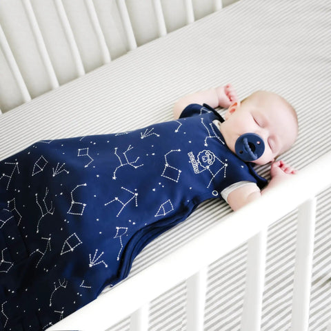 Baby in crib wearing Ultimate Baby Sleep Sack For 4 Season Merino Wool Sleeping Bag With Organic Cotton Outer Night Sky