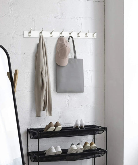 Wall Mounted Coat Rack With Eight Hooks Wood Base Modern White Entryway And Bedroom Organizer For Coats Scarves Towels Leashes And More Space Saving Durable Metal Hooks installed in a room with items hanging.