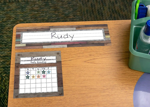 Home Sweet Classroom Flat Name Plates 36 Pack on student desk, displaying 'Rudy' with reading chart, 11-1/2 x 3-1/2 inches.